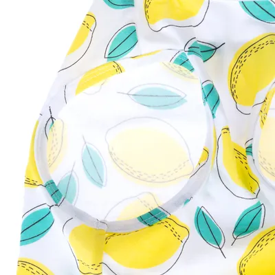Tissu blanc avec motif citrons jaunes et feuilles vertes, coutures visibles autour d’une ouverture ronde. Matière textile clairement visible.