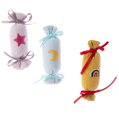 Drei Stoffspielzeuge in Bonbonform mit Schleifen: rosa mit Stern, blau mit Mond, gelb mit Regenbogen. Ideal für Haustierbespassung.