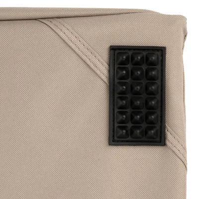 Primer plano de una superficie de tela beige con parche cuadrado de goma negro con textura de puntos.