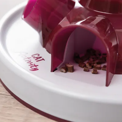 Leksak med texten 'Cat Activity', röd plastdesign, fack med små godbitar synliga.