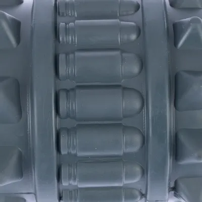 Surface en plastique gris avec reliefs cylindriques et picots visibles, gros plan sur la texture du produit sans marque ni texte apparent.