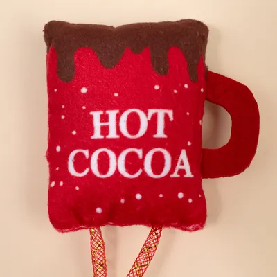 Red plush toy in the shape of a cup with brown chocolate glaze and white text 'HOT COCOA'.