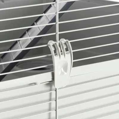 Zoom sur une cage en métal blanc avec attache en plastique blanche et rampe intérieure visible.