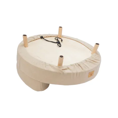 Runde beige Plattform mit Holzbeinen und Spannseil, geeignet für Montage oder Zubehör. Sichtbares Label auf Stoffumrandung.