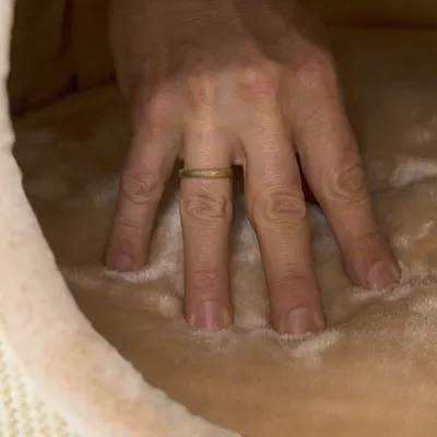 Hand pressing soft beige material to demonstrate the product's padding and comfort.