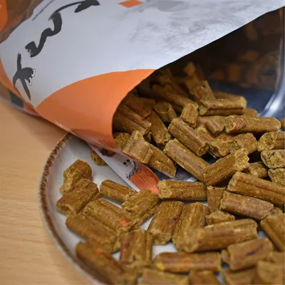 Open verpakking met bruine, langwerpige snacks op een bord. Gedeeltelijk zichtbare merknaam op de verpakking.