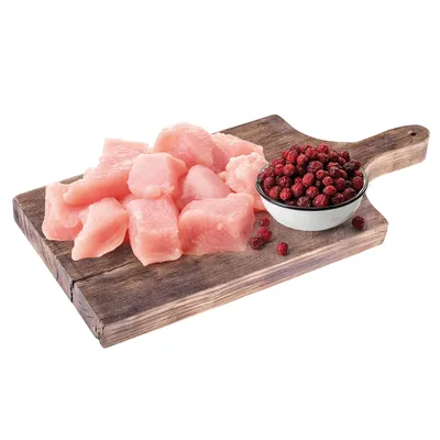 Frische Fleischstücke und rote Beeren in einer Schale auf einem Holzbrett, Zutaten für Tiernahrung.