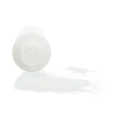 Barattolo di plastica bianca con fori sul tappo, rovesciato e con polvere bianca versata accanto. Nessun marchio o testo visibile.