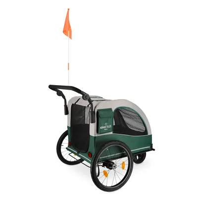 Grüner Fahrradanhänger mit orangefarbener Sicherheitsflagge, zwei grossen Rädern und Netzfenstern. Aufdruck: Nomad Tales.