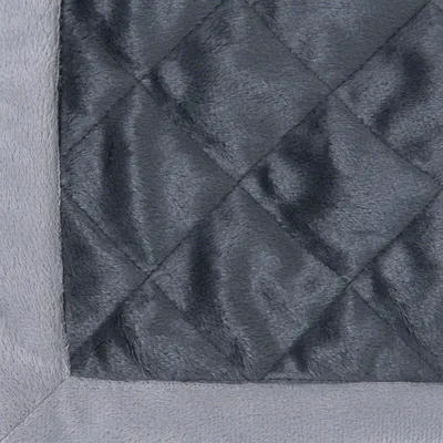 Nahaufnahme eines gesteppten, grauen Stoffmaterials mit weicher Oberfläche und Rand aus hellgrauem Plüsch.