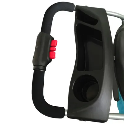 Poignée de poussette avec mousse noire, deux boutons rouges et plateau en plastique noir comprenant un porte-gobelet et deux compartiments ouverts.
