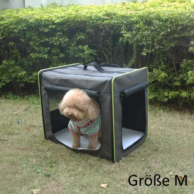 Chien dans une caisse de transport en tissu gris avec poignées, posée sur l’herbe. Texte visible : Größe M.