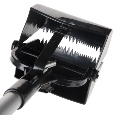 Pelle ramasse-crottes noire en plastique avec mâchoires dentelées et manche métallique visible, vue rapprochée sur le mécanisme de fermeture à ressort.