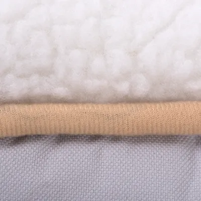 Detail tří vrstev materiálu: horní bílá vrstva s chlupatou strukturou, střední béžová pletenina, spodní šedá textilie. Materiály jsou jasně viditelné.