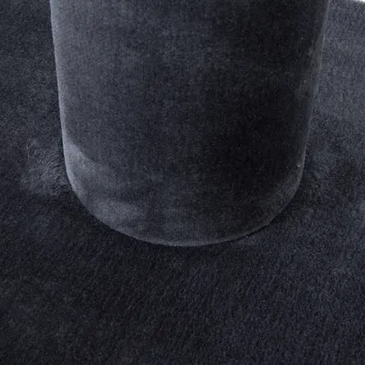 Gros plan sur une base ronde et un poteau recouverts de tissu noir, sans autres éléments visibles.