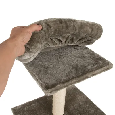 Main tenant le bord d’une plateforme en tissu gris sur arbre à chat, poteau recouvert de sisal visible. Matériaux : tissu peluche et sisal.