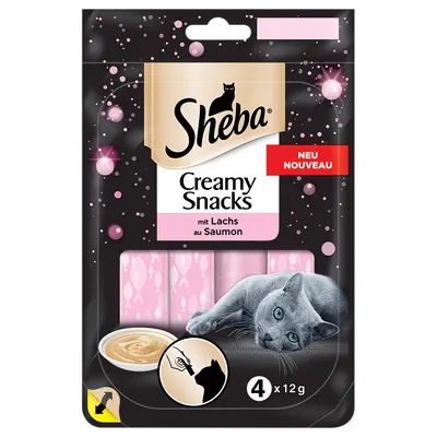 Sheba Creamy Snacks mit Lachs au Saumon, 4 x 12 g. Pakkauksessa vaaleanpunaiset annospussit, kuva harmaasta kissasta ja kulhosta, merkintä NEU NOUVEAU.
