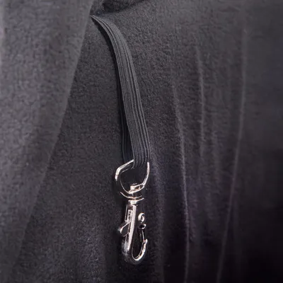 Mousqueton métallique fixé à une sangle élastique noire, attaché sur un tissu noir à texture polaire. Aucun texte ou marque visible.