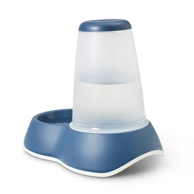 Dispenser per acqua in plastica trasparente e blu, con serbatoio verticale e ciotola integrata alla base.
