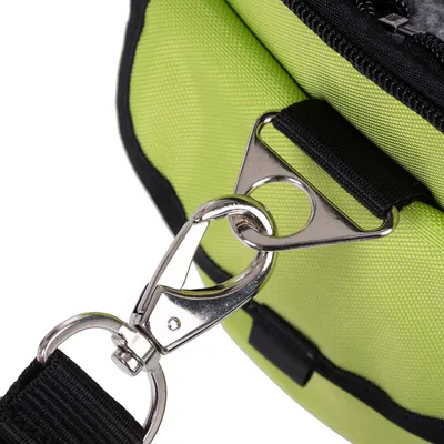 Gros plan sur une attache métallique avec mousqueton fixée à une sangle noire et un sac en tissu vert à fermeture éclair visible.