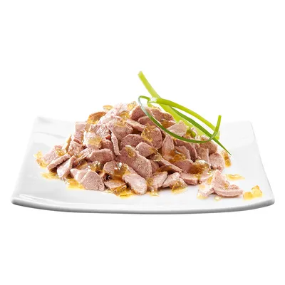 Chunks of meat in jelly served on a white plate with green garnish, showing the texture and appearance of the food product.