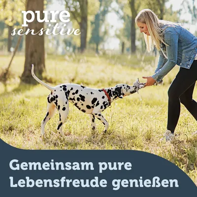 Dalmatiner spielt mit einer Person im Freien. Text: Gemeinsam pure Lebensfreude geniessen. pure sensitive.