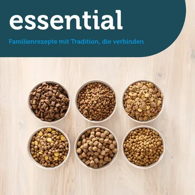essential. Familienrezepte mit Tradition, die verbinden. Sechs Schalen mit verschiedenen Sorten Trockenfutter auf hellem Holzuntergrund.