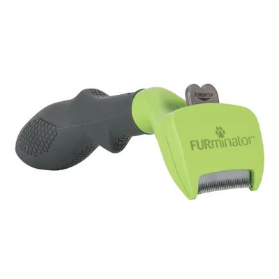 Cepillo verde y negro con mango antideslizante, marca FURminator visible en la carcasa. Botón metálico con texto 'FURejector' y púas metálicas expuestas.