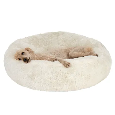 Animal lying on a large, round, fluffy cream-coloured bed, demonstrating the use and size of the product.