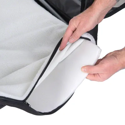 Handen openen een witte fleece hoes met rits, zichtbaar is de binnenvulling van het kussen. Materiaal: fleece en schuim.