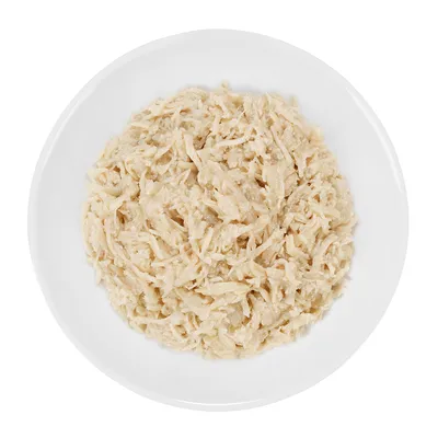 Ciotola bianca con alimento umido per animali composto da carne sfilacciata chiara, senza altri ingredienti visibili.