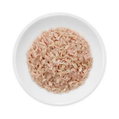 Wit bord met natvoer bestaande uit lichtroze, fijn gesneden stukjes vlees of vis, zonder zichtbare verpakking of merknaam.