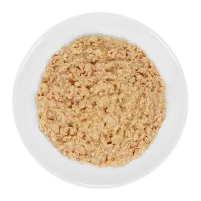 Piatto bianco con alimento umido tritato di colore beige, presentato senza confezione o marchio visibile.