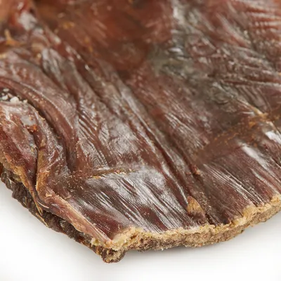 Närbild av torkat kött, brun yta med synlig struktur och fibrer.