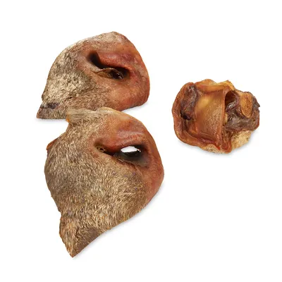Kuivattuja sian kuonoja ja yksi sian korva luonnollisina puruherkkuina, näkyvissä karva ja rapea koostumus.