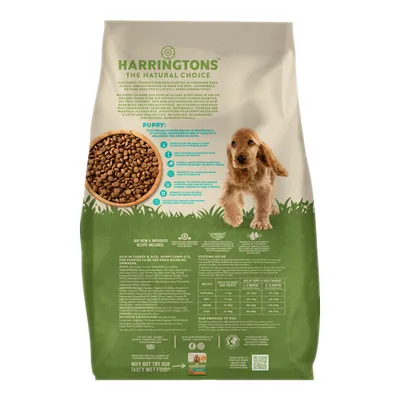 Bag showing Harringtons The Natural Choice puppy food with visible feeding guide, ingredients list, and a bowl of dry kibble. Key features and nutritional information are displayed.
