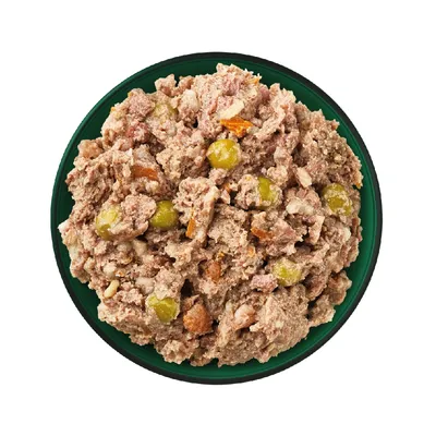 Bowl filled with chunky wet pet food containing visible pieces of meat and vegetables such as peas and carrots.