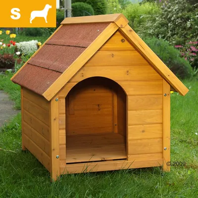 Niche pour chien taille S en bois avec toit à deux pentes recouvert de tuiles rouges, entrée en arc, posée sur l’herbe. Pictogramme chien et lettre S visibles en haut à gauche.