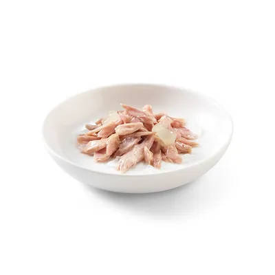 Ciotola bianca con bocconcini di carne rosa in salsa, presentati come alimento umido per pet. Nessun marchio o testo visibile.