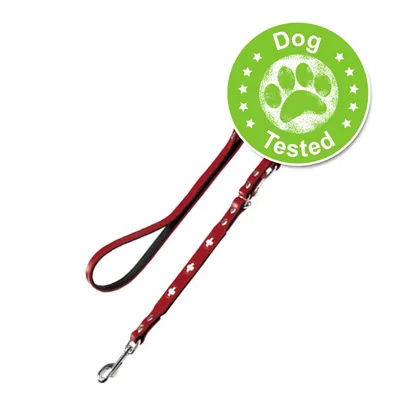 Rød hundesnor med hvide kors og metalspænde. Grøn badge med teksten 'Dog Tested' og poteaftryk synlig på billedet.