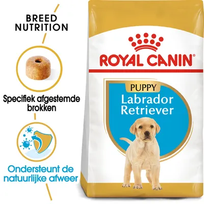 Royal Canin Puppy Labrador Retriever hondenvoer, verpakking met merknaam en tekst: Specifiek afgestemde brokken, Ondersteunt de natuurlijke afweer. Afbeelding van een brok en hond.