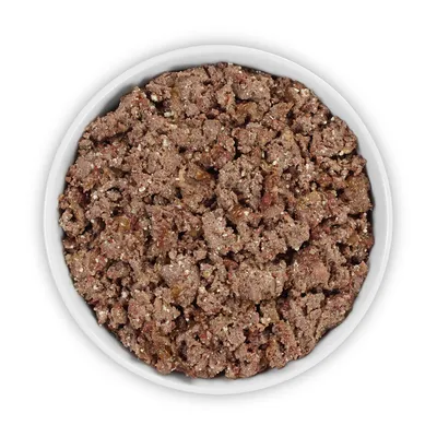 Nahaufnahme einer weissen Schale mit zerkleinertem Nassfutter, braune und rote Stücke sichtbar.