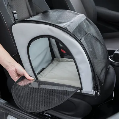 Transport bag with mesh window and zip, secured on a car seat. Hand opens the front flap.