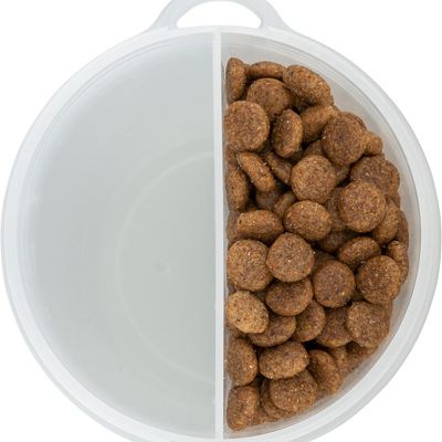 Okrągłe plastikowe pudełko z dwoma przegródkami, jedna pusta, druga wypełniona brązowymi kawałkami suchej karmy.
