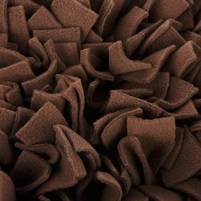 Gros plan sur des bandes de tissu marron en polaire, disposées en couches denses et superposées.