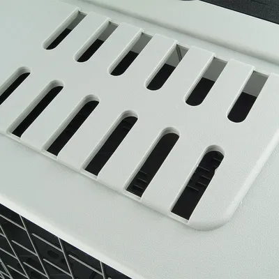 Close-up of a white plastic lid with ventilation slots, part of a pet carrier.