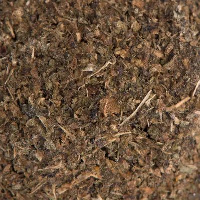Close-up of loose, ground feed material with brown and green plant components.