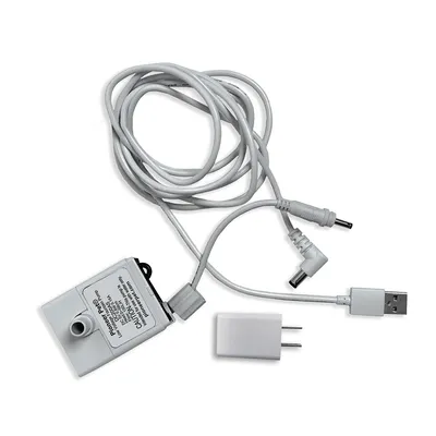 Bomba Pioneer Pet con cable USB, adaptador de corriente y conectores visibles. Texto en la bomba: 'Pioneer Pet Co., Ltd. Model: P-001 Input: DC 5V/1A'. Bomba Pioneer Pet con cable USB, adaptador de corriente y conectores visibles. Texto en la bomba: 'Pioneer Pet Co., Ltd. Model: P-001 Input: DC 5V/1A'.