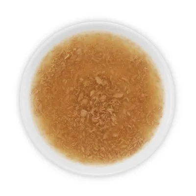 Primo piano di una ciotola bianca con consistenza liquida marrone e piccoli pezzi di carne. Visualizzazione del contenuto del prodotto.