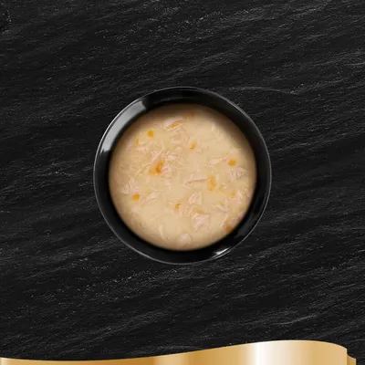 Tigela preta com sopa clara, visíveis pequenos pedaços de carne e legumes.